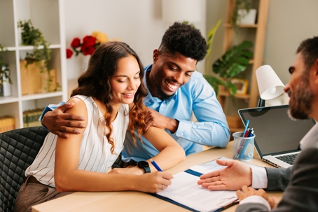young couple signing a document in an office